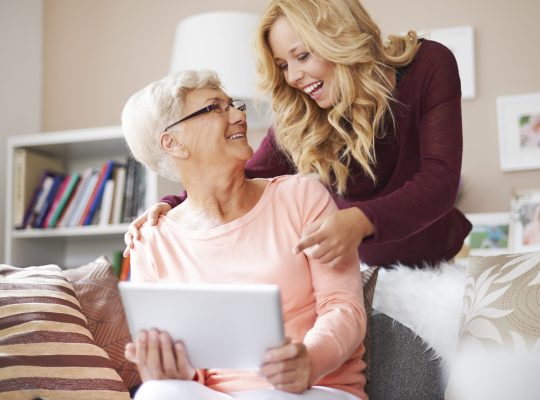 Sweet blonde girl showing something funny on digital tablet